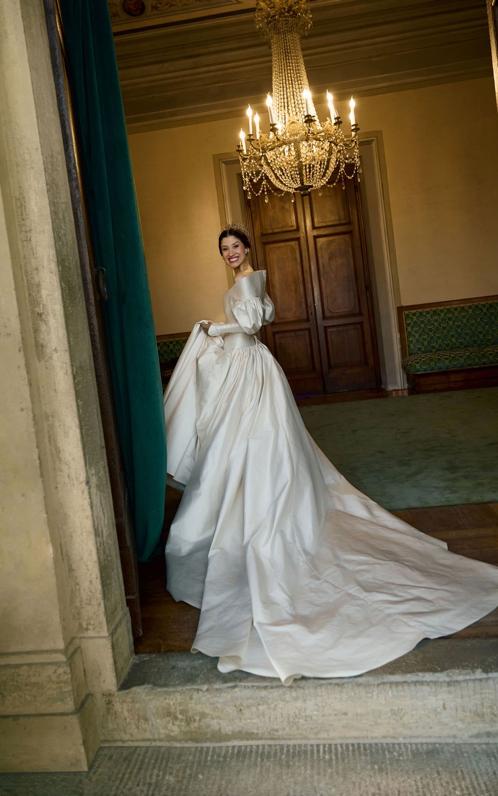 Image may contain Chandelier Lamp Person Clothing Dress Fashion Formal Wear Gown Wedding Wedding Gown and Bench